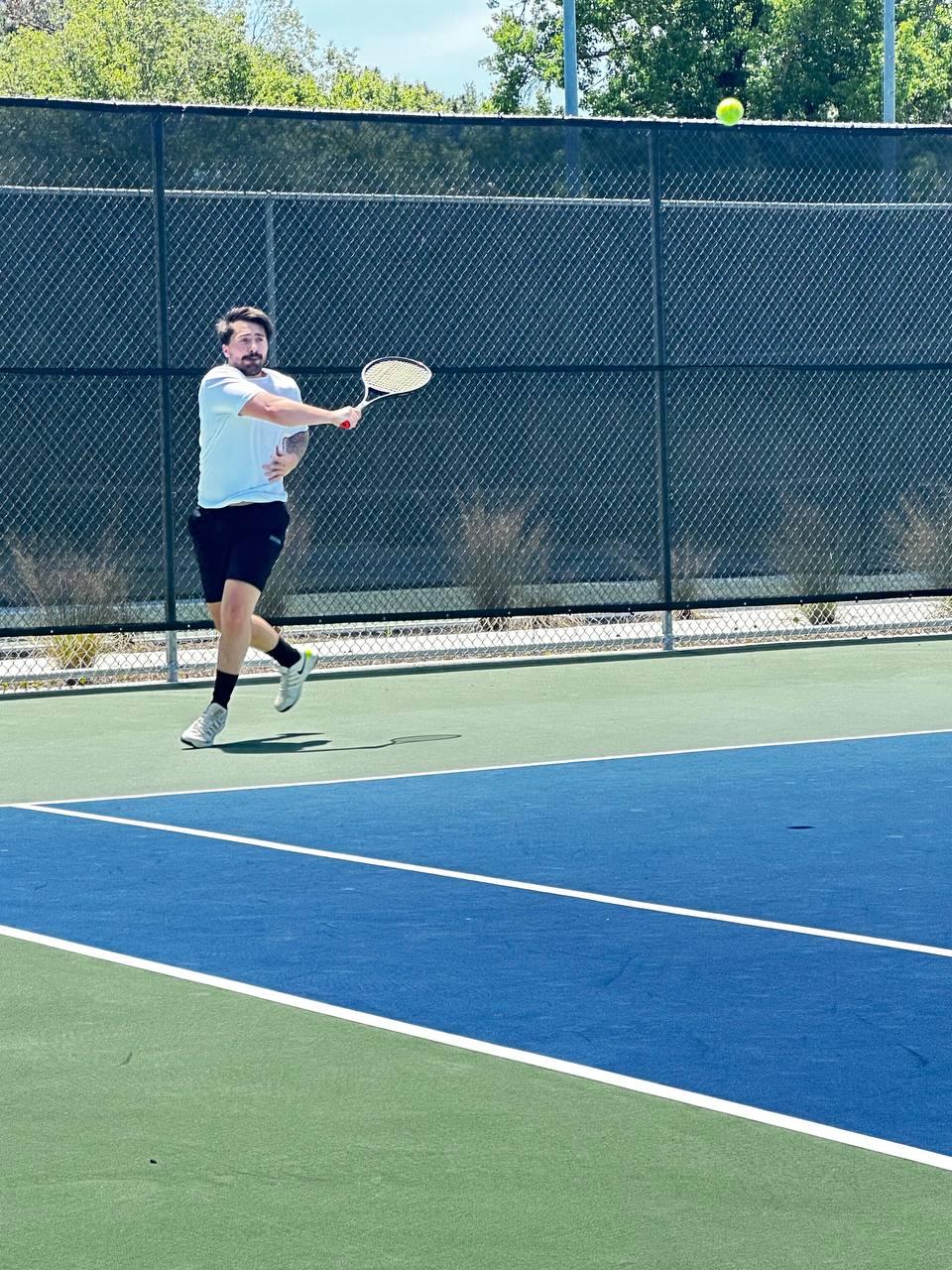 Cooper Barnes hitting a leaping two-handed backhand on a hard court